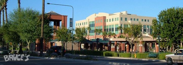 Modern office and retail building with palm trees along a sunny downtown street corner.