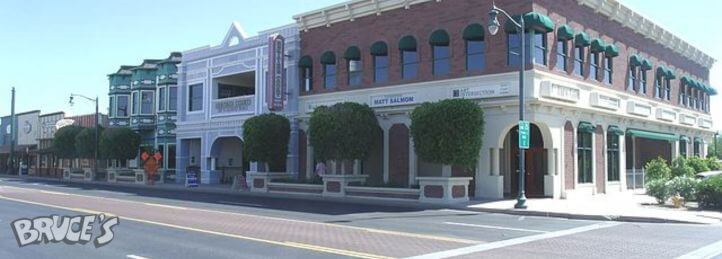 Historic downtown corner building with brick facade, arched windows, and storefronts along a quiet street.