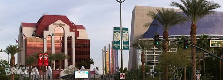 Downtown city street with modern office buildings, palm trees, and traffic lights at an intersection.