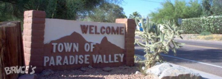 Welcome sign for the Town of Paradise Valley beside a desert road with cacti and landscaping.