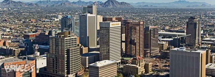 Aerial view of downtown Phoenix skyline with high-rise office buildings and mountains in the background.
